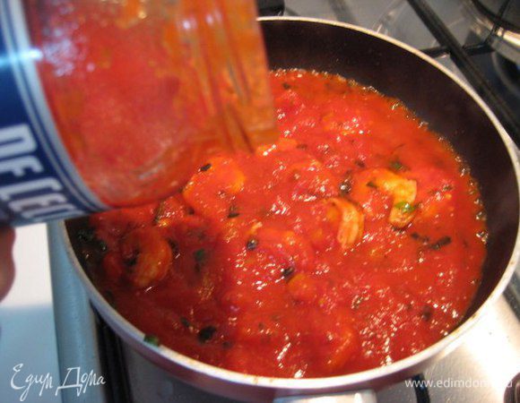 Добавить соус. У меня готовый соус "Арраббиата", он уже острый. Если такого нет, то посыпать смело креветки красным жгучим перцем. Довести до кипения соус. 