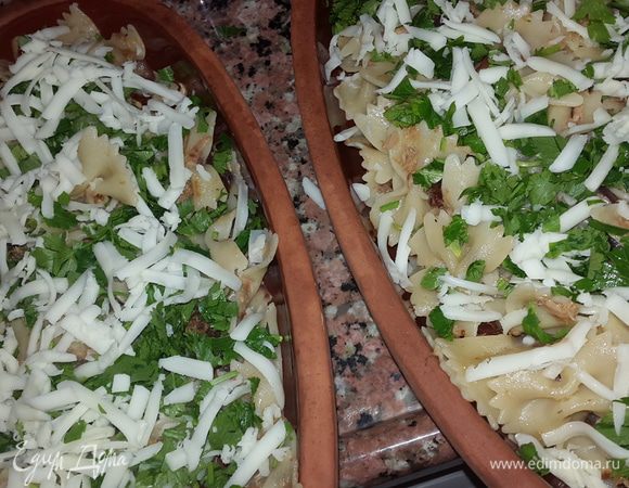 Пасту откинуть на дуршлаг и соединить с тунцом и томатами. Достать тарелки из духовки, выложить пасту, посыпать петрушкой и сыром и отправить в духовку на 3 минуты.