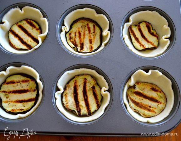 Теперь в формочки для маффинов выложить кружки из теста бОльшего диаметра. На дно формочек положить по кружочку баклажана.