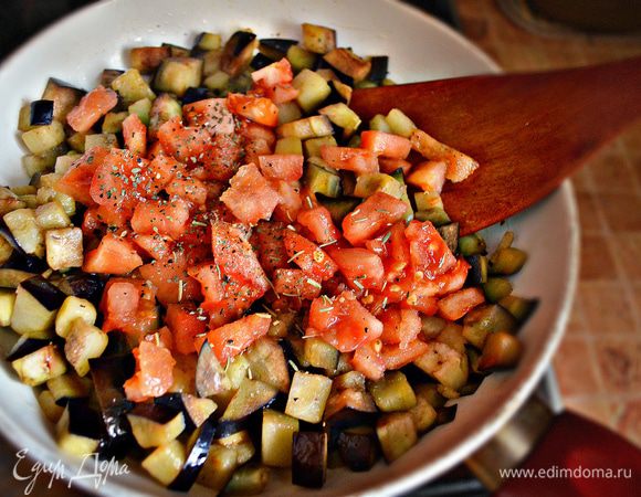 Помойте и порежьте кубиками баклажан. На подготовленном чесночном масле обжарьте баклажаны до размягчения, периодически помешивая, чтобы не подрумянились. Добавьте порезанные кубиками помидоры (кожицу от помидор предварительно необходимо снять). Добавьте соль, смесь 4 перца, базилик, орегано и перемешайте. Потушите ещё 5 мин.