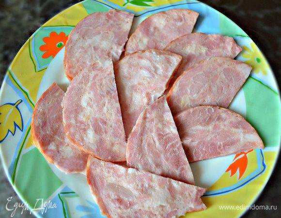 Ветчину тонко нарежьте ломтиками и затем разрежьте пополам.