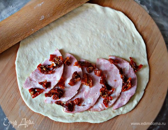 Каждую часть раскатайте. На половинку круга, отступая 1,5-2 см положите 1 начинку: ветчину, сверху вяленые помидоры.