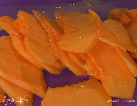 Тыкву почистить, нарезать тонкими ломтиками и сбрызнуть 2 ст. ложками оливкового масла.