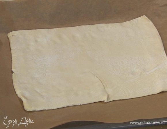 Тесто предварительно разморозить, затем один пласт слегка раскатать, так чтобы получился прямоугольник, и уложить его на противень.