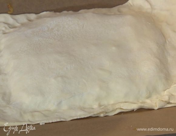 Второй пласт теста раскатать в прямоугольник чуть большего размера, чем первый, и накрыть им сверху пласт с начинкой, плотно прижав края.