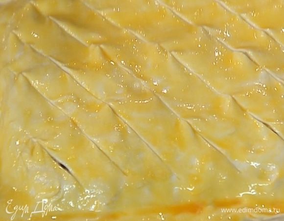 Желток посолить, слегка взбить, смазать пирог и острым ножом сделать диагональные неглубокие надрезы.