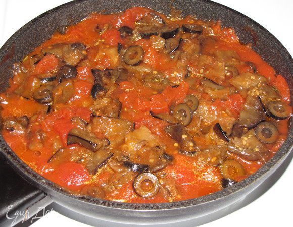Приготовим соус.
Баклажаны и помидоры (очищенные от кожицы) нарезать кубиками около 1 см, оливки колечками. Зубчик чеснока раздавить плоской стороной лезвия ножа, бросить на сковороду, в которой нагревается оливковое масло, дать ему пожелтеть. Затем чеснок удалить. Добавить баклажан, помешивая, поджарить до румяности. Добавить оливки. Через пару минут добавить порезанные помидоры вместе с соком и продолжать тушить еще 10 минут. Посолить и поперчить соус.
Вместо свежего баклажана у меня были консервированные запеченные баклажаны. Поэтому я просто прогрела томаты с оливками, а затем добавила нарезанные на кусочки консервированные баклажаны.