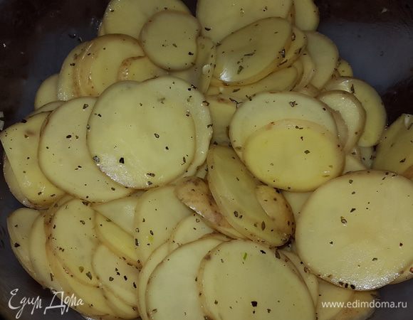 Картофель выкладываем в глубокую миску, солим, перчим, добавляем травы, чеснок, немного масла от вяленых томатов и перемешиваем руками.