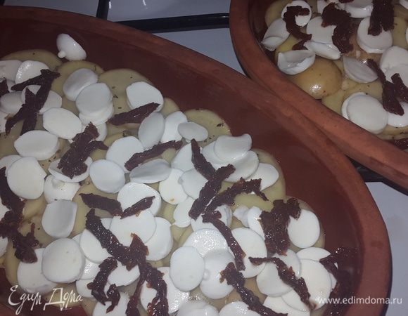 Тарелки смазываем маслом от томатов, выкладываем слой картофеля, слой моцареллы и томаты, немного солим.