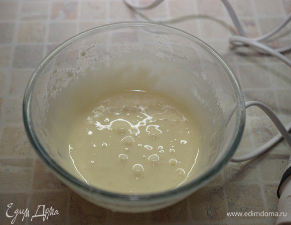 Затем тонкой струйкой влить горячее молоко. Все время размешивать массу венчиком.