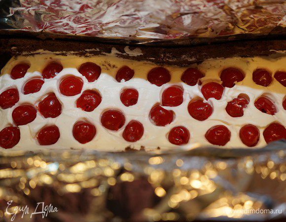 Накрыть мусс первой полоской бисквита. Немного прижать. Коктейльную вишню процедить через сито от лишнего сока. Взбить охлажденные сливки с сахаром и уложить на бисквит (оставить пару столовых ложек на украшение торцов рулета). Выложить коктейльную вишню на крем шантильи, немного утопив её в крем.