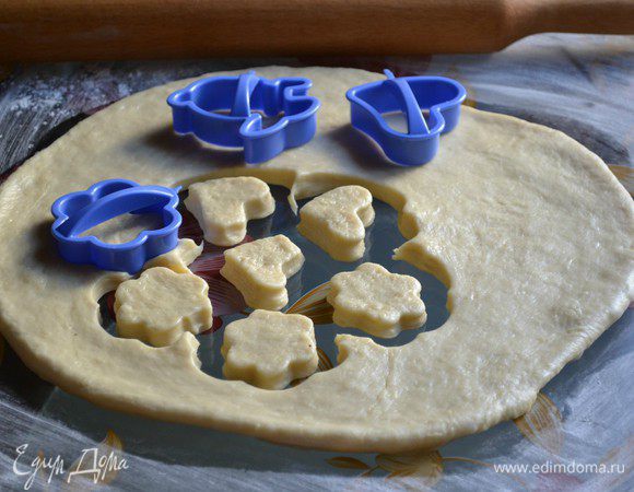 Рабочую поверхность присыпать мукой, раскатать тесто толщиной примерно 2 см. Формочками вырезать фигурки. Если формочек нет, сделайте как я: стаканом вырежьте кружки и сделайте надрезы с 4-х сторон, не доходя до середины. В процессе жарки получатся цветочки.