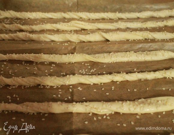Затем выложите тесто на рабочую поверхность, отрежьте небольшой кусок , присыпьте кунжутом и раскатайте скалкой, смазанной растительным маслом, в пласт толщиной 0,5 см.
Разрежьте на полоски шириной в 2 см и скрутите в жгут. Повторите с каждой полоской и уложите на противень.
Смажьте каждый жгут разведенным в молоке крахмалом и присыпьте кунжутом.
Время расстойки 20 минут.
Выпекать при 200 градусах до золотистого цвета.
Следующую партию палочек приготовьте с прованскими травами.