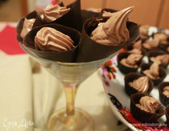 Взбить мягкий сыр с растопленным шоколадом. Крем положить в кондитерский мешок. 
Достать из холодильника шоколадные формочки и наполнить их сливочным кремом.