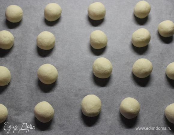 Катаем из теста шарики размером с грецкий орех и выкладываем их на застеленный пергаментом противень на расстоянии друг от друга не менее 2-х сантиметров, так как печенье вырастет в объеме при выпечке.
Из данного количества получается приблизительно 18-20 шариков.
