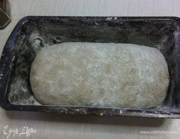 Выложите тесто на стол, припудренный мукой. Обомните тесто, сформируйте булку. Уложите в форму. Накройте сверху полотенцем и поставьте в теплое место на 1 час или пока заготовка не увеличится в объеме вдвое.