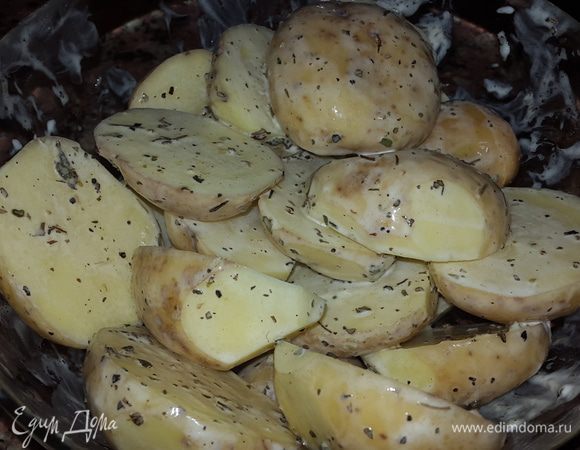 Некрупный картофель моем, обсушиваем, разрезаем вдоль на 2 части и выкладываем в миску. Солим, перчим, добавляем травы, оливковое масло, майонез и тщательно обмазываем каждую дольку.