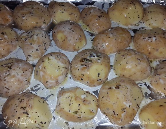 Противень застилаем фольгой (матовой стороной вверх) и выкладываем картофель срезом вниз.