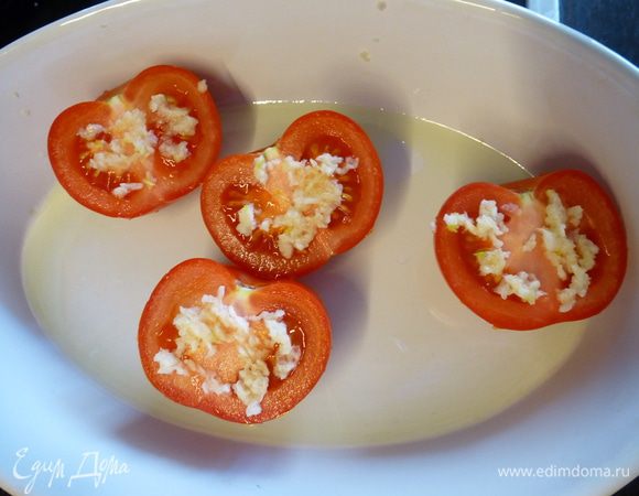 Помидоры разрезаем пополам. Форму смазываем оливковым маслом, выкладываем помидоры. На каждую половинку выдавливаем зубчик чеснока. Ставим в духовку под гриль на 10 минут.