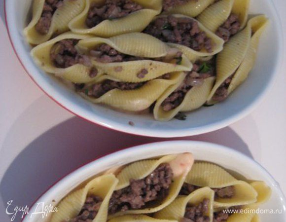 Ракушки нафаршировать фаршем. Духовку разогреть до 180С.
На дно керамических порционных формочек вылить половину соуса бешамель, плотно выложить ракушки, смазать оставшимся соусом, посыпать тертым пармезаном и дольками сливочного масла.