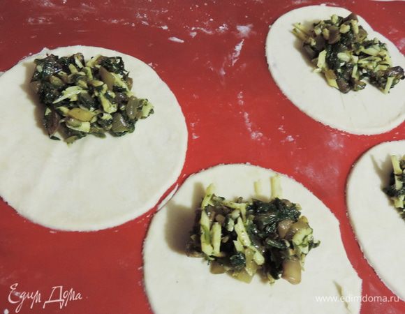 Тесто раскатываем на щедро посыпанной мукой поверхности, само тесто тоже припудриваем мукой, чтобы оно не липло к скалке.
Для того, чтоб получился эффект слоености не нужно раскатывать тесто очень тонко, 3-4 мм будет в самый раз.
Вырезаем из теста круги нужного диаметра, у меня 12 см. На одну половину кладем подготовленную начинку.