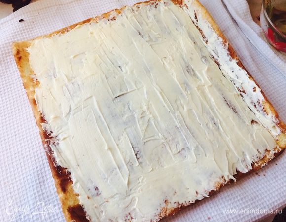 Развернуть рулет, смазать бисквит сиропом. Затем, тонким слоем распределить светлый крем по поверхности коржа.