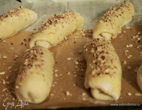 Булочки положить на противень и оставить в тепле и покое на 30 минут.
Через 30 минут смазать булочки смесью молока с яйцом и присыпать измельченным фундуком.