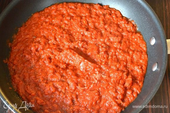 Тем временем приготовим соус. Для этого разогреть в глубокой сковороде оливковое масло. Выложить измельченные томаты в собственном соку. Добавить все остальные ингредиенты (специи можете брать по своему вкусу), довести до кипения и потушить соус на слабом огне около 40 минут. Он должен стать достаточно густым. Готовый соус снять с огня и дать ему остыть.