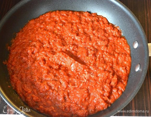 Тем временем приготовим соус. Для этого разогреть в глубокой сковороде оливковое масло. Выложить измельченные томаты в собственном соку. Добавить все остальные ингредиенты (специи можете брать по своему вкусу), довести до кипения и потушить соус на слабом огне около 40 минут. Он должен стать достаточно густым. Готовый соус снять с огня и дать ему остыть.