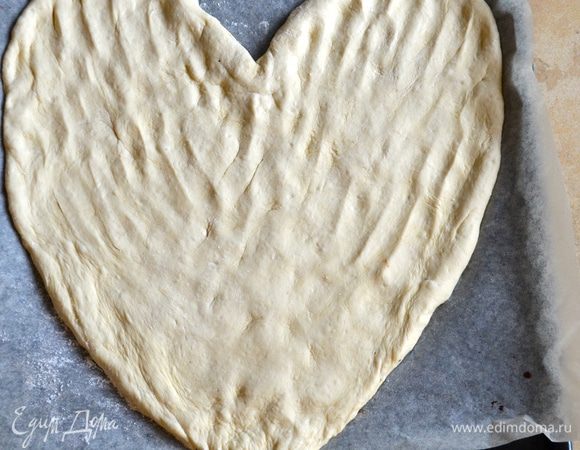 Духовку включить разогреваться на 220 С. 
Готовое тесто обмять, перенести на противень, застеленный бумагой и, помогая себе руками, придать пицце форму сердца. Накрыть полотенцем и отставить на 10 минут.