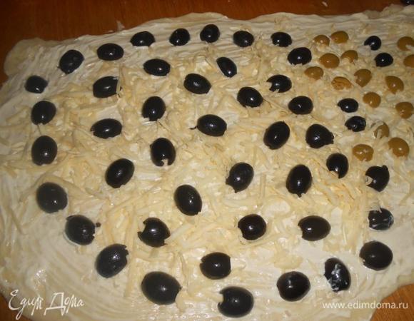 Раскатать тесто не очень тонко. Поверхность смазать маслом. Выложить оливки и маслины на тесто, посыпать тертым сыром и травами.