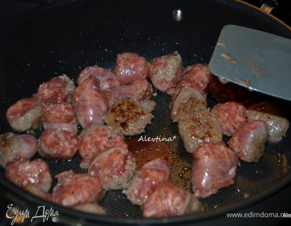 Отварить пасту орзо в курином бульоне, посолив 8-10 мин. Можно развести бульон водой.
Обжарить колбаски, порезав на части примерно 4 минут, сняв кожицу по желанию. Добавить порезанный чеснок мелко и обжаривать еще 1 мин.