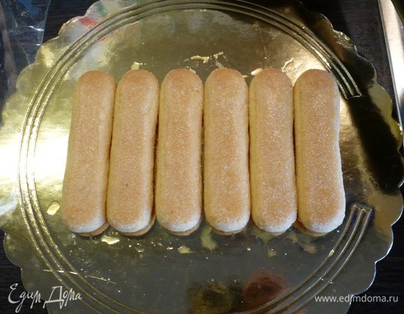 Выжимаем из апельсинов сок. У меня из двух апельсинов получилось примерно стакан сока. Мне понадобилось только 2/3 стакана. 
В сок для аромата можно добавить немного апельсинового ликера Куантро, но это по желанию.
Каждое печенье полностью погружаем в сок на 1-2 секунды и выкладываем на тарелку для торта. Для первого ряда нам понадобиться 6 штук.