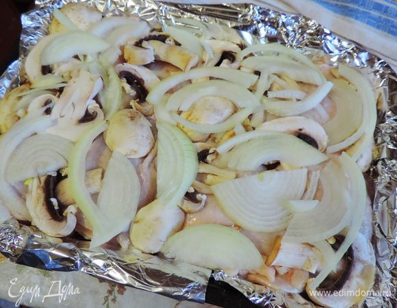 На лук выкладываем окорочка, кожицей вверх. Я рекомендую для запекания брать верхнюю часть, она более мясистая.
На окорочка выкладываем порезанные пластинками шампиньоны и оставшийся лук, нарезанный тонкими полукольцами. Можно немного посолить.