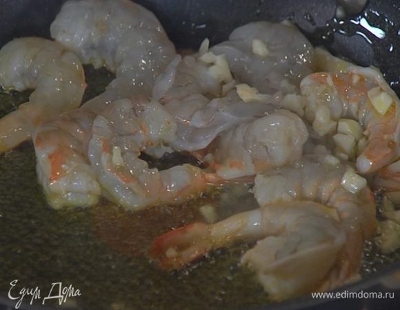 Разогреть в сковороде оливковое масло, выложить креветки, чеснок и слегка обжарить, чтобы креветки стали розовыми.
