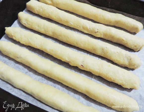 Тесто с начинкой завернуть плотным рулетиком, края защипать. Положить на противень, застеленный пергаментом, швом вниз.