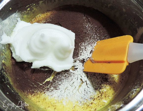 Теперь просеиваем сверху на желтковую массу треть сухой смеси, добавляем треть белков и аккуратно перемешиваем лопаткой движениями снизу вверх от краев к центру.