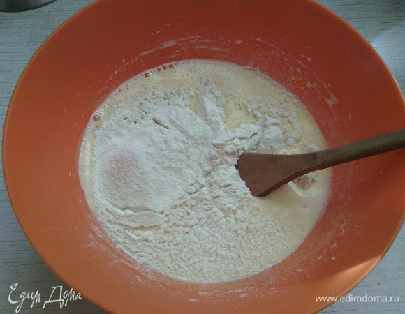 В отдельную емкость просейте муку.
Смешайте муку с разрыхлителем и щепоткой соли (можно еще раз просеять всю смесь, для большей "воздушности" бисквита).

Понемногу добавляйте муку в яичную массу, медленно и аккуратно размешивая ложкой, движениями снизу вверх.  
Тут очень важно именно не взбивать, а просто осторожно перемешивать!