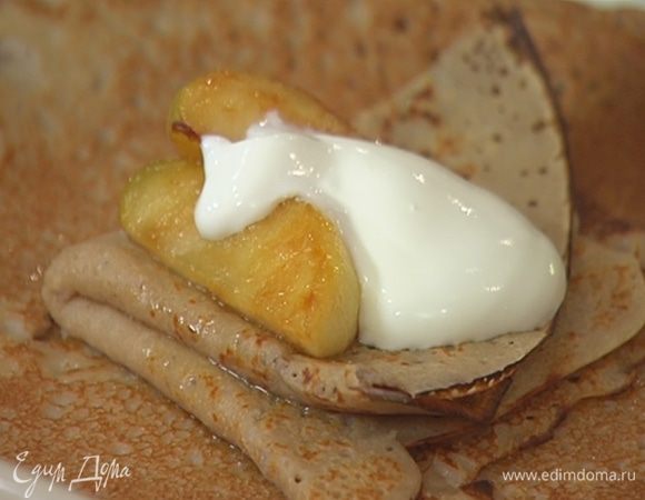 Готовые блины смазать медовым соусом и свернуть треугольниками, сверху выложить закарамелизированные яблоки и сметану.