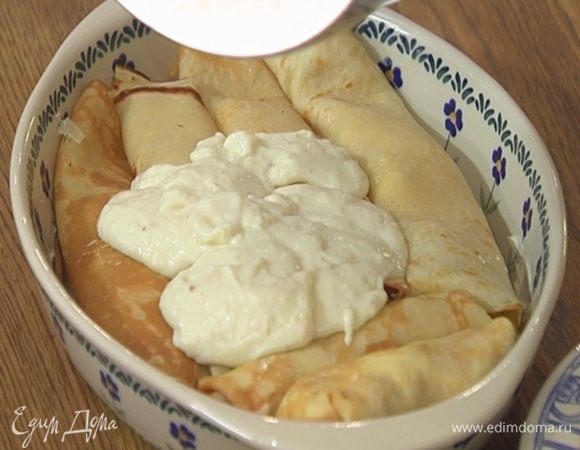 Жаропрочную керамическую форму смазать оставшимся сливочным маслом, выложить свернутые блины и залить соусом бешамель.