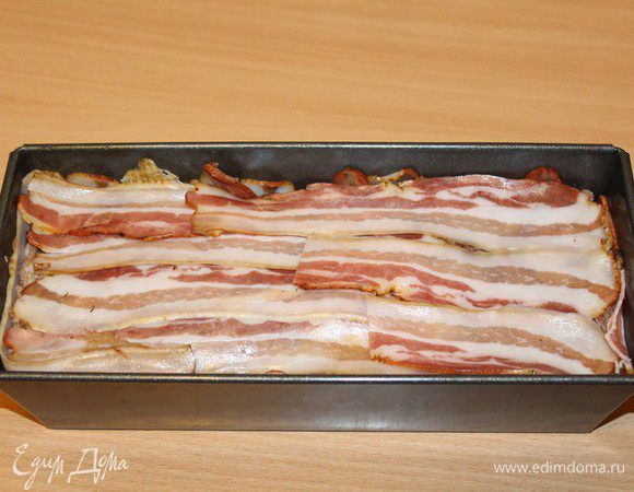 Закрыть беконом. Накрыть форму фольгой и отправить в разогретую до 180–200°C духовку. Запекать 1,5 часа. Образовавшуюся жидкость после запекания нужно слить.