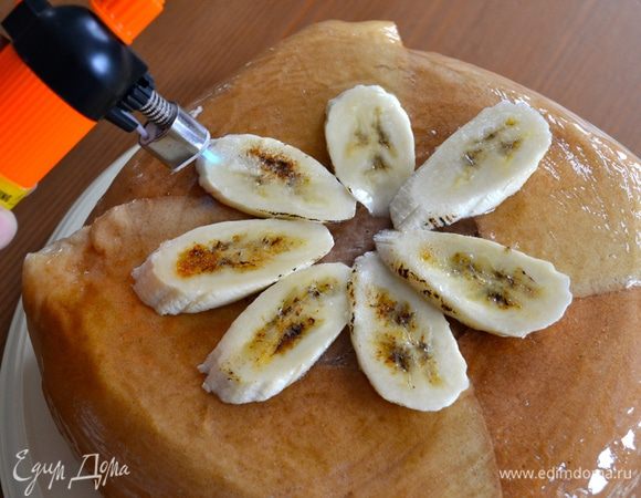 Перед подачей на стол переложить торт на 1,5 часа в холодильник. И непосредственно перед сервировкой достать торт, развернуть пищевую пленку, перевернуть на сервировочное блюдо. Снять бортики, дно и убрать пищевую пленку. Приготовить желатин для украшения тортов согласно инструкциям и с помощью кисточки смазать им весь торт. Можно присыпать тертым шоколадом (я этого не сделала). Сверху можно украсить торт нарезанным бананом, как вам нравится! Присыпать сверху кусочки банана белым сахаром, если есть газовая горелка, карамелизовать сахар. Если нет, оставить просто кристалликами.