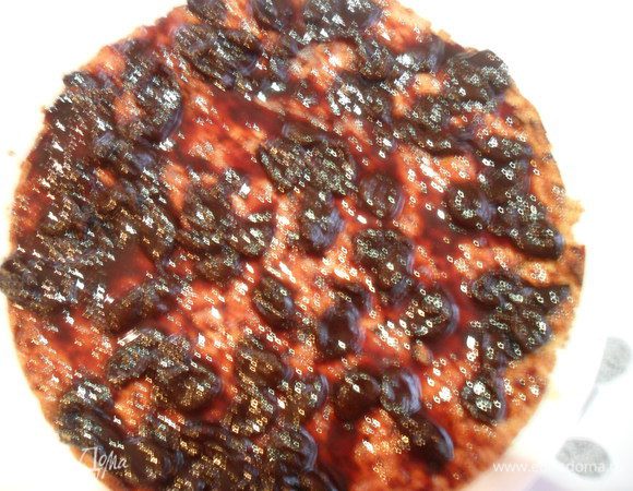 На блюдо выкладываем песочный корж и смазываем его вишневым джемом.