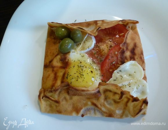 Блинчик переворачиваем. В "тарелочку" выкладываем пластики помидора, пластики сыра "Бри", разбиваем яйцо, солим, посыпаем итальянскими травами. Закрываем сковороду крышкой и жарим на среднем огне до необходимой готовности яйца.

Готовый блинчик украшаем оливками и сбрызгиваем оливковым маслом.
Мужской завтрак готов! Приятного аппетита!