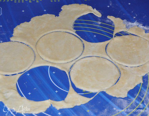 Включить разогреваться духовку до 180 градусов. Противень застелить пергаментом. Для удобства раскатывания, тесто лучше разделить на 2 части. Одну часть пока вернём в холодильник, а с другой будем работать. Охлаждённое тесто раскатать. Выемкой подходящего размера (у меня чашка диаметром 10 см) вырезать круги. 