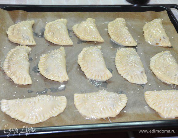 Заклеить пирожки. Края хорошо придавить вилкой. Смазать пирожки взбитым яйцом. Можно посыпать кунжутом (с ним вкуснее!). Зубочисткой сделать небольшое отверстие посередине пирожка, для выхода пара.