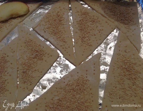 Слоеное тесто толщиной 5 мм разрезать на небольшие треугольники. Проколоть их все хорошо вилкой, посыпать кунжутом либо миндальными лепестками, у меня был кунжут.