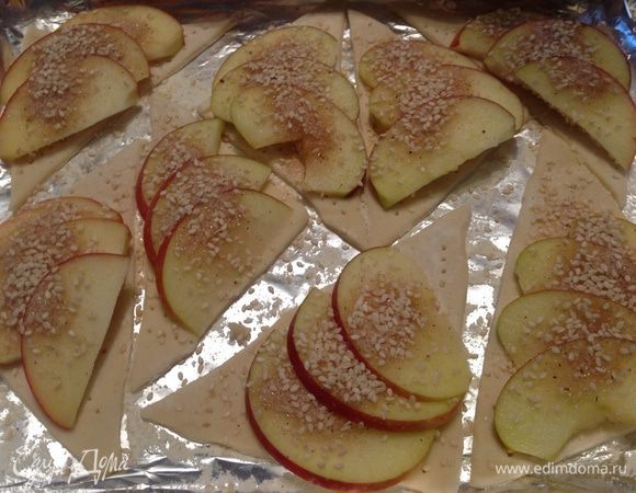 Сверху кунжута выложить порезанные яблоки, посыпать сахаром с корицей и кунжутом. Выпекать при температуре 180 градусов 15-20 минут, до румяной корочки.