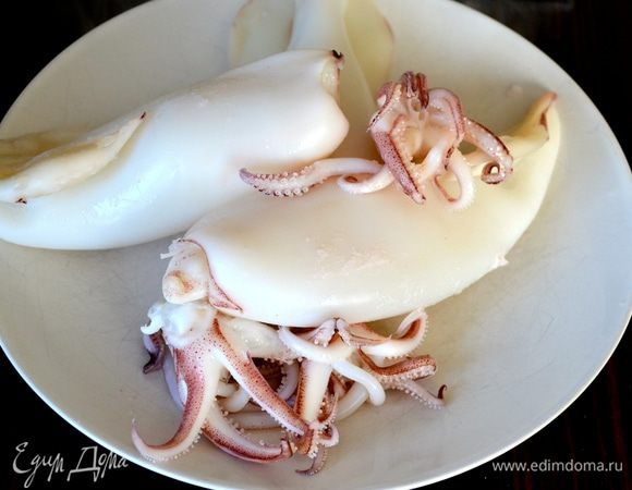 Достать кальмаров из кипящей воды и опустить в ёмкость с холодной водой. Очистить и нарезать кольцами.