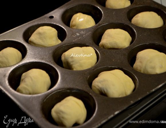 Формочки для маффинов смажьте маслом. Тесто поделите на 2 равные части, затем одну часть поделите ровно на 12 частей. Также поступите со второй частью. Скатайте в шарики и разложите по формочкам, поставьте в теплое место на расстойку примерно на 50–60 мин. Затем смажьте верх сметаной, сливками или белком. Можно сверху присыпать луковой специей или кунжутным семенем. Поставьте в разогретую духовку на 180°C на 25–30 минут.